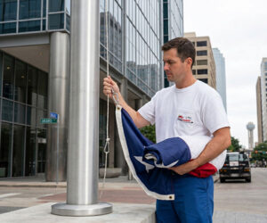 A technician from Flag Mobile replacing a Texas flag in front of a Dallas coprporate building.